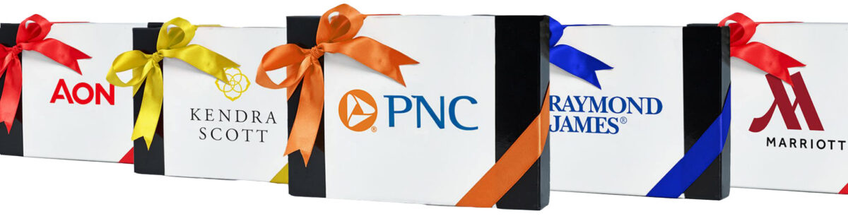 Box of Chocolates with custom logos for clients such as PNC, Kendra Scott, AON, Raymond James, Marriott with multi-colored bows.